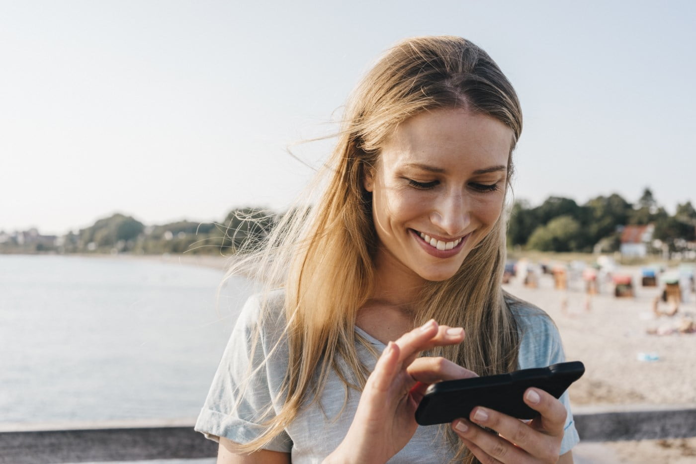Jente med mobiltelefon på stranden