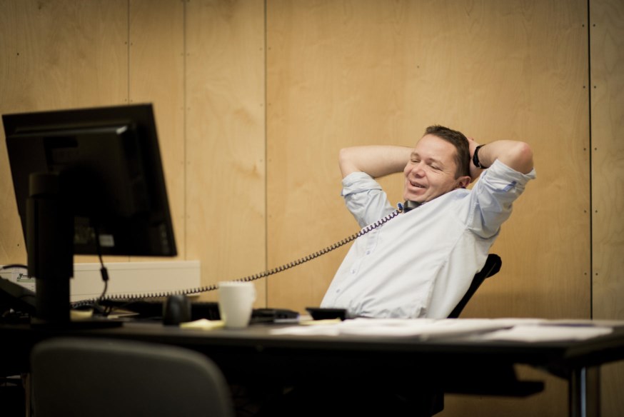 Mann sitter ved kontorpulten og snakker i telefon. foto